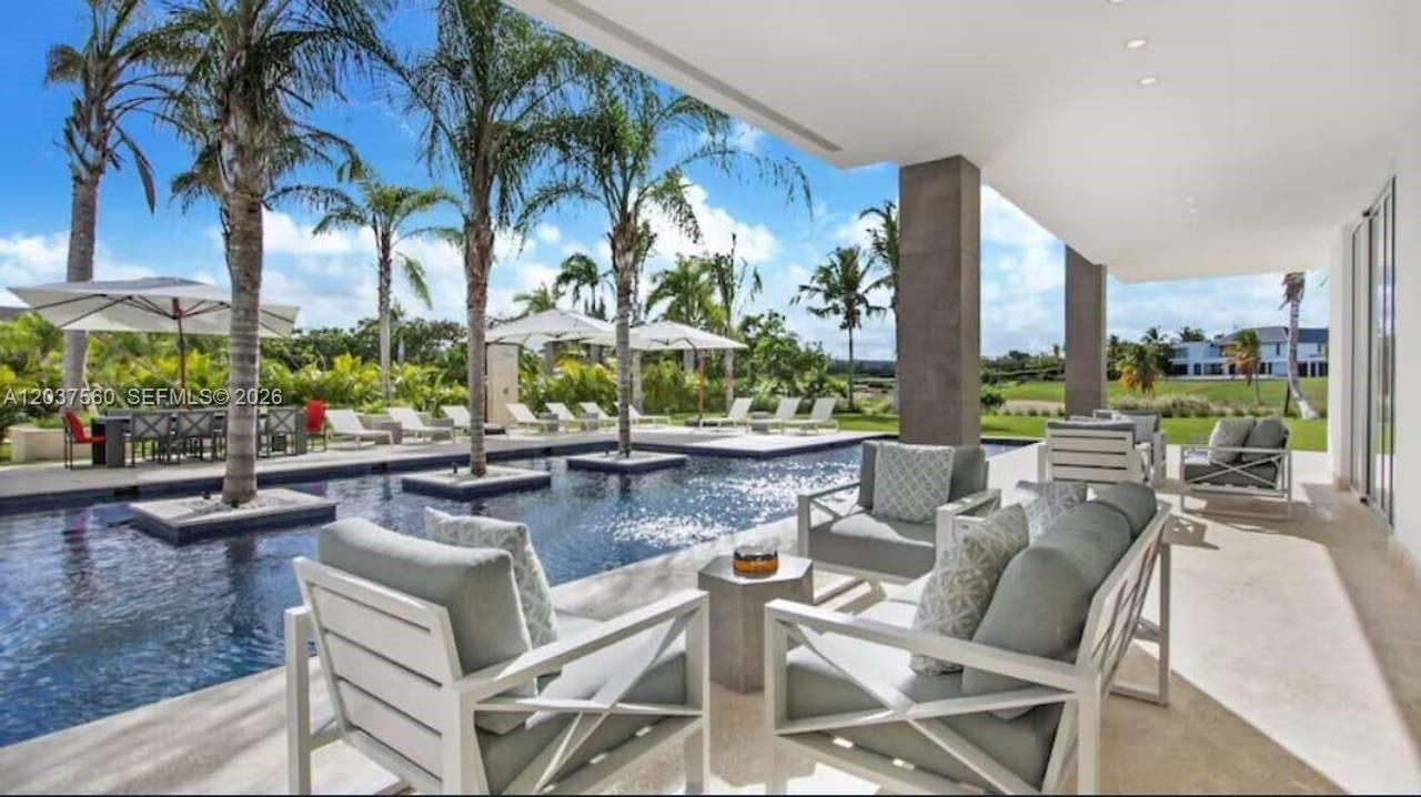 A covered patio overlooks a swimming pool with palm trees and lounge chairs — 0 Caleton estate 1, FL