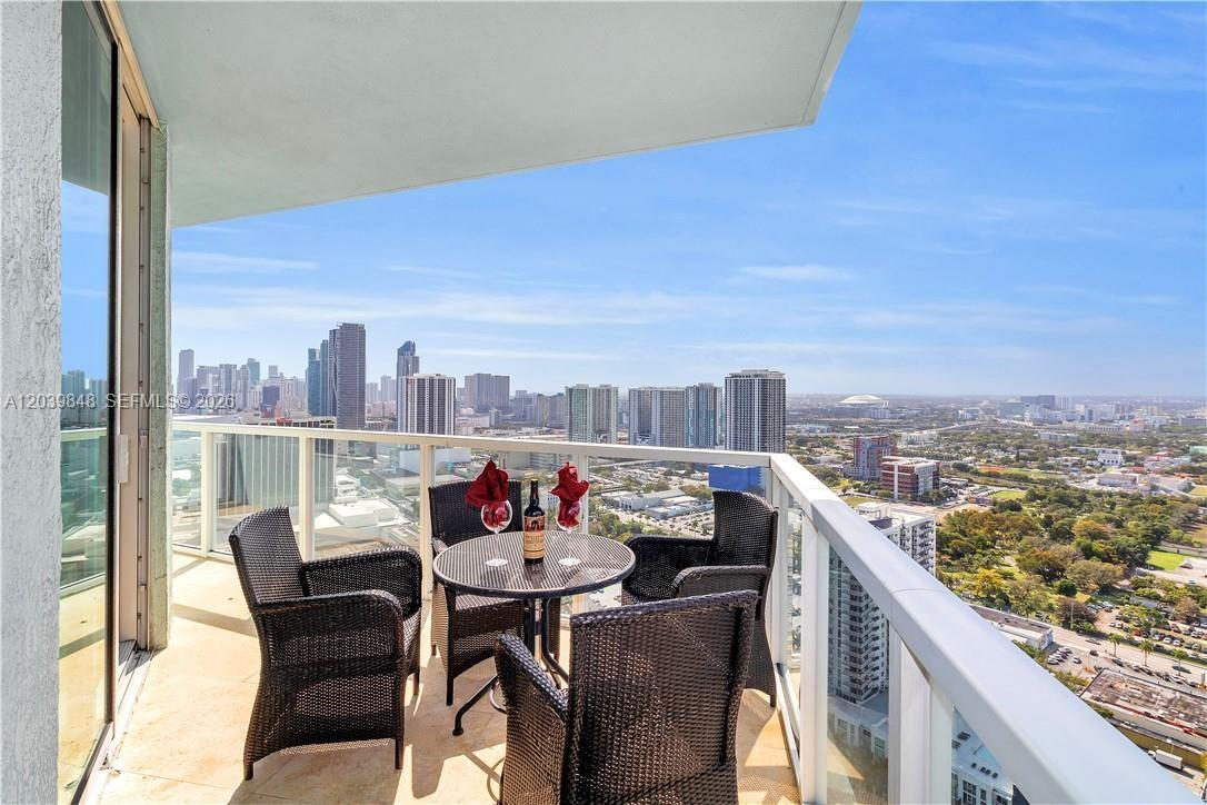 A balcony with a bistro set overlooks a city skyline and a green landscape — 1900 N Bayshore Dr # 3518, Miami FL 33132, MIAMI, FL