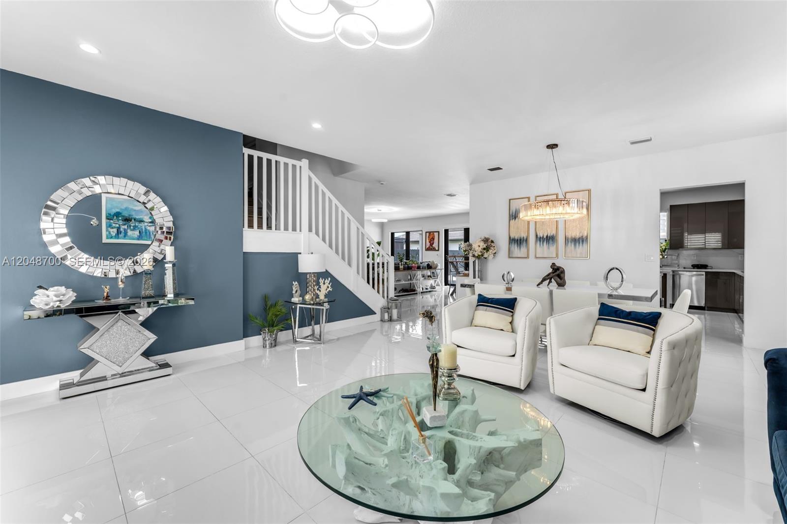 A bright, open-concept living and dining area features white tile floors and a blue accent wall — 1810 SW 144th Ave, Miami FL 33175, MIAMI, FL