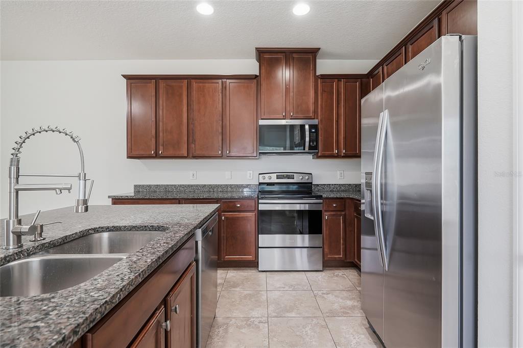 A kitchen features dark wood cabinets, granite countertops, stainless steel appliances, and a center island — 4097 70TH TERRACE N, PINELLAS PARK, FL