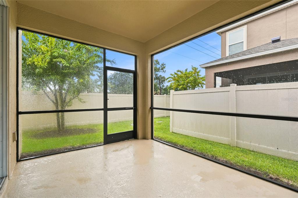 A screened-in patio with a concrete floor overlooks a fenced backyard and a neighboring house — 4097 70TH TERRACE N, PINELLAS PARK, FL