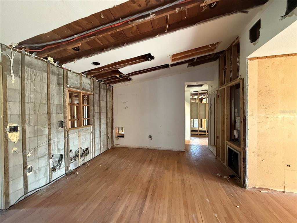 An interior room under renovation features exposed wood ceiling beams, concrete block walls, and hardwood floors — 1015 S PALM AVENUE, ORLANDO, FL