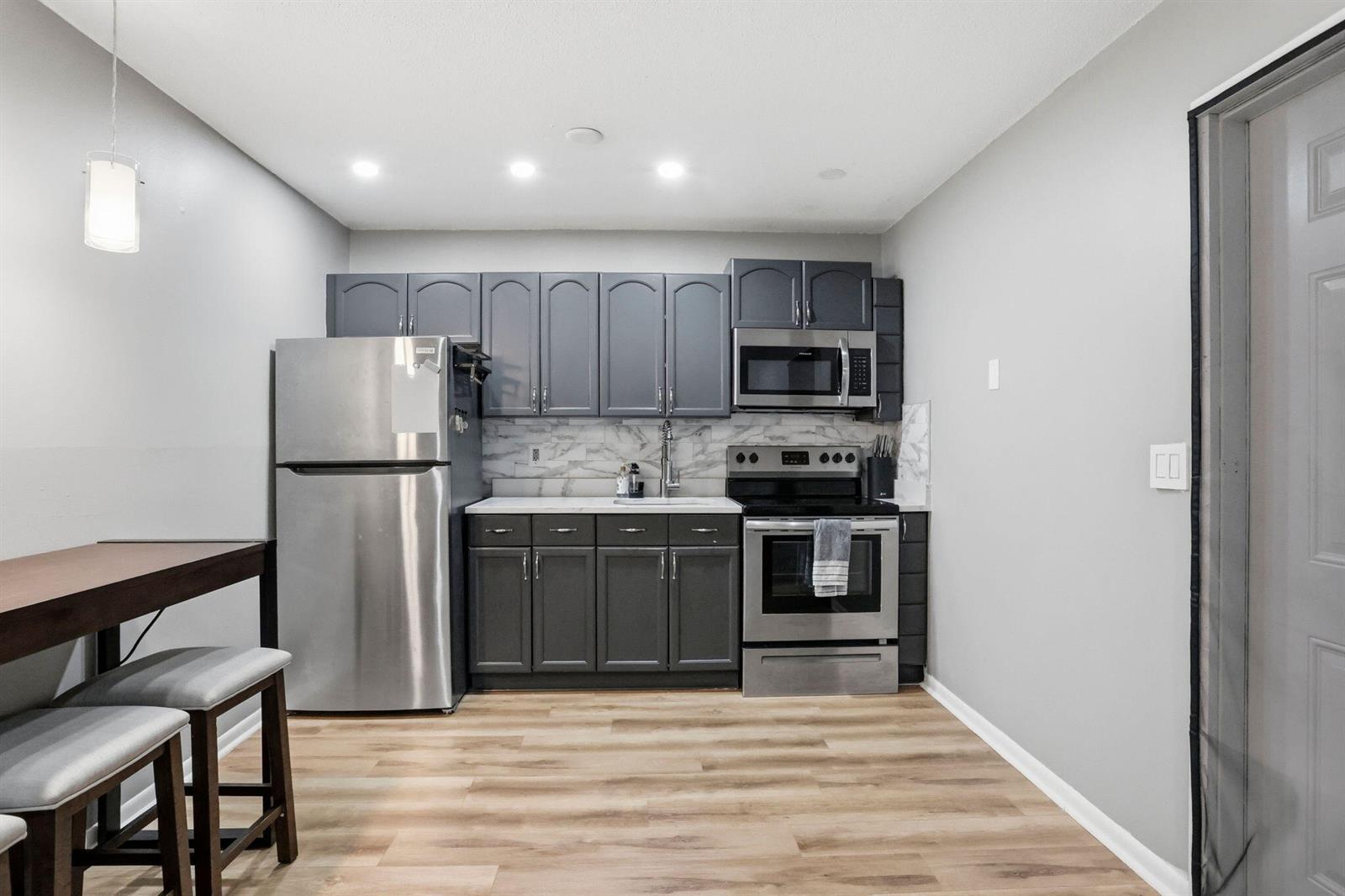 A kitchen features dark gray cabinets, stainless steel appliances, and light wood-look flooring — 1204 S Lake Drive E # 3, Lantana FL 33462, LANTANA, FL