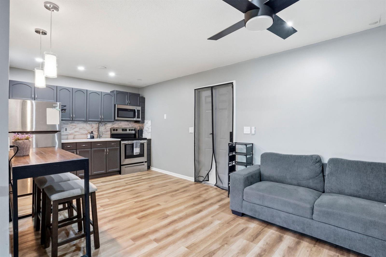 A kitchen and living area feature gray cabinets, stainless steel appliances, and wood-look flooring — 1204 S Lake Drive E # 3, Lantana FL 33462, LANTANA, FL