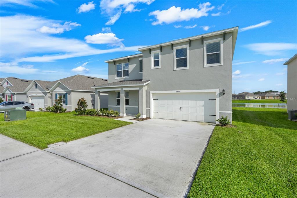 A two-story suburban house with a gray stucco exterior and a two-car garage — 5252 MASSER ROAD, ST CLOUD, FL