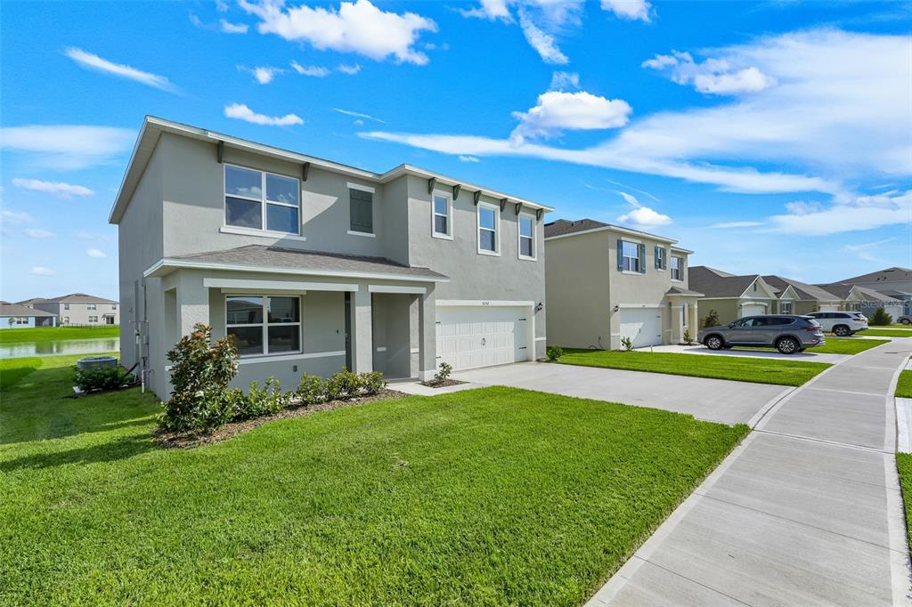 A two-story suburban house with a gray stucco exterior, a garage, and a front lawn — 5252 MASSER ROAD, ST CLOUD, FL