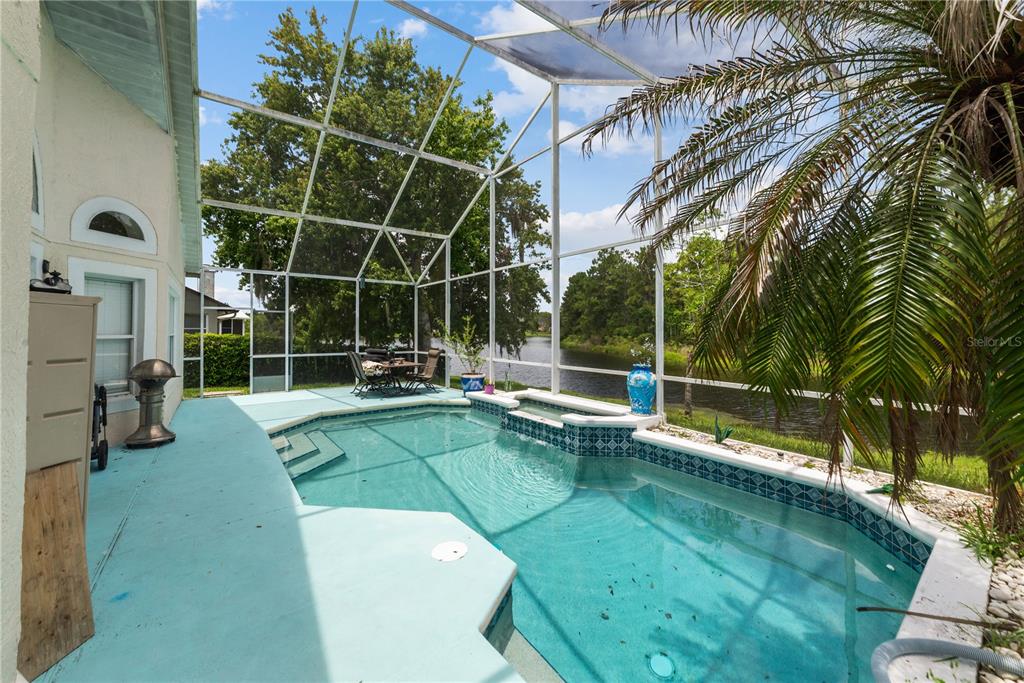 A screened-in pool area features a turquoise deck, a small pool, and a water view — 3840 BECONTREE PLACE, OVIEDO, FL
