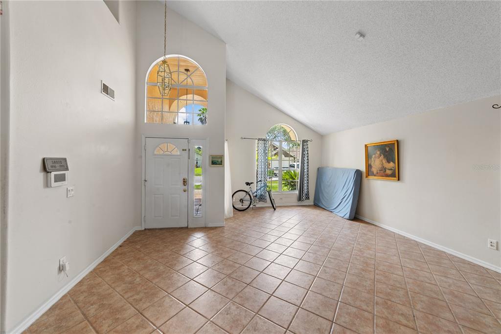 A high-ceilinged entryway with tile flooring, a front door with sidelights, and arched windows — 3840 BECONTREE PLACE, OVIEDO, FL