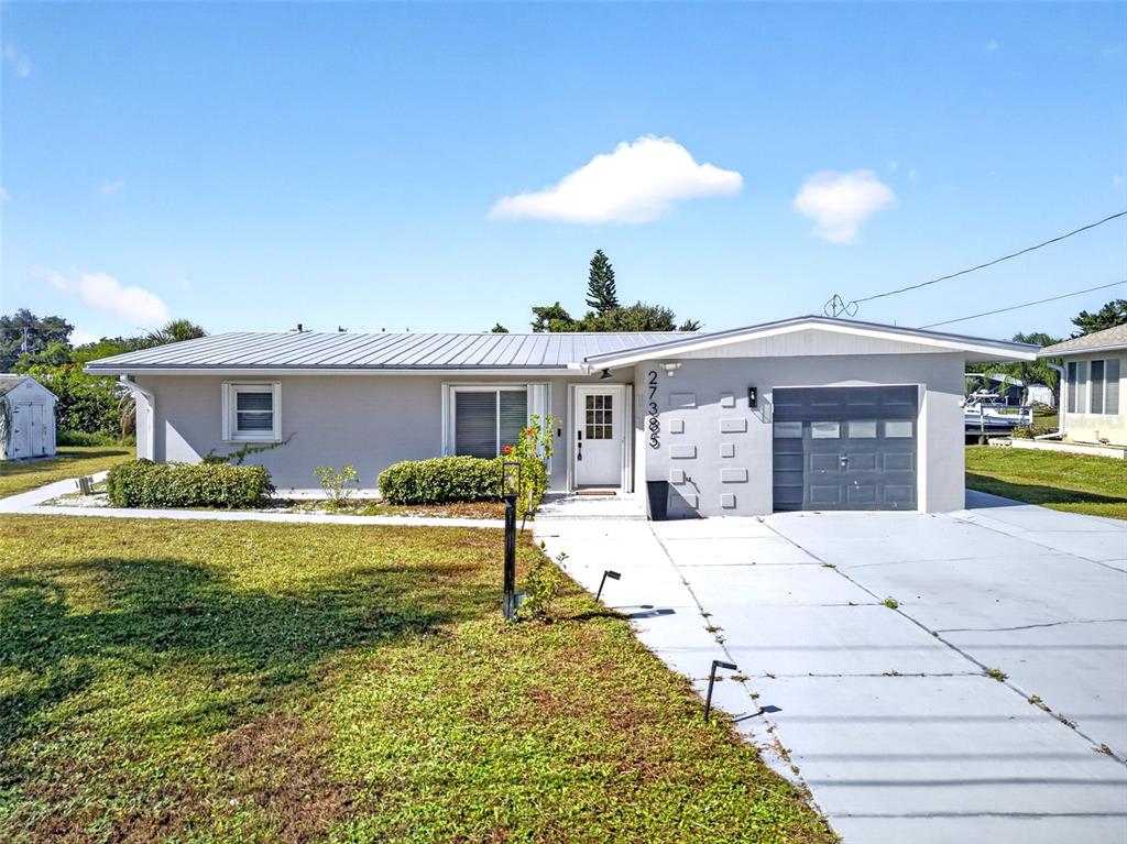 A single-story house with a metal roof, gray exterior, and an attached garage — 27385 VOYAGEUR DRIVE, PUNTA GORDA, FL