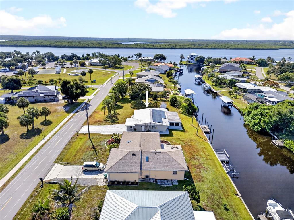 An aerial view shows waterfront houses along a canal with a road nearby — 27385 VOYAGEUR DRIVE, PUNTA GORDA, FL