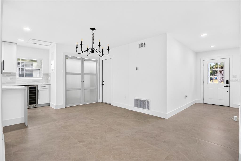 A bright, open-concept dining area with white walls, large tile flooring, and a modern chandelier — 27385 VOYAGEUR DRIVE, PUNTA GORDA, FL