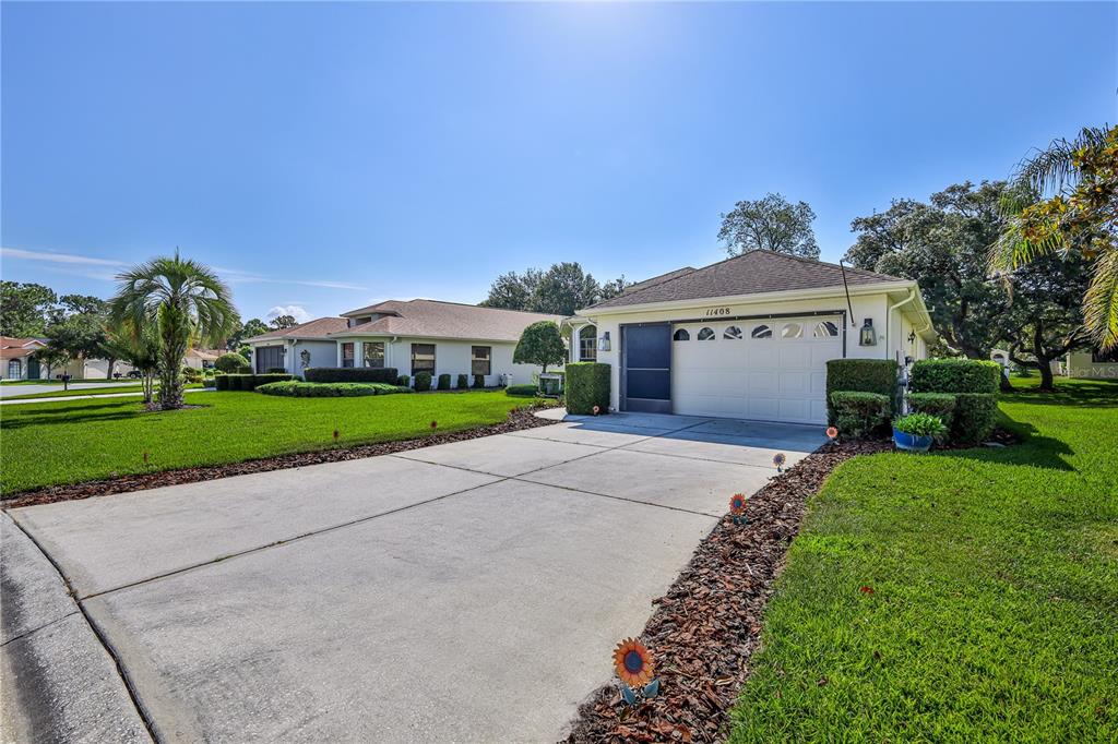 A single-story house with a white garage door and a concrete driveway under a clear sky — 11408 DEERCROFT COURT, SPRING HILL, FL