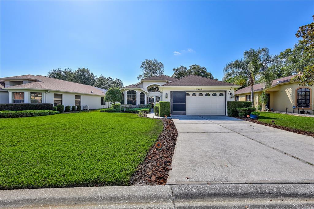 A single-story house with a white garage, a concrete driveway, and a green lawn — 11408 DEERCROFT COURT, SPRING HILL, FL