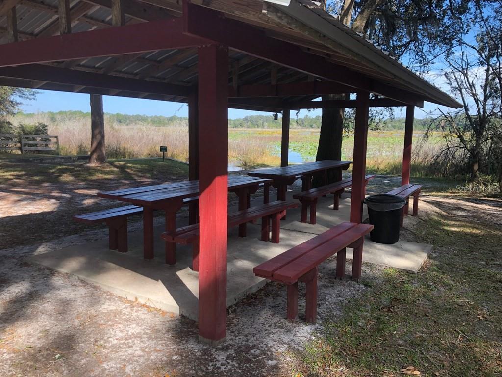 A covered picnic pavilion with wooden tables and benches overlooks a grassy marsh area — 1.77 acres NW 73 STREET, CHIEFLAND, FL