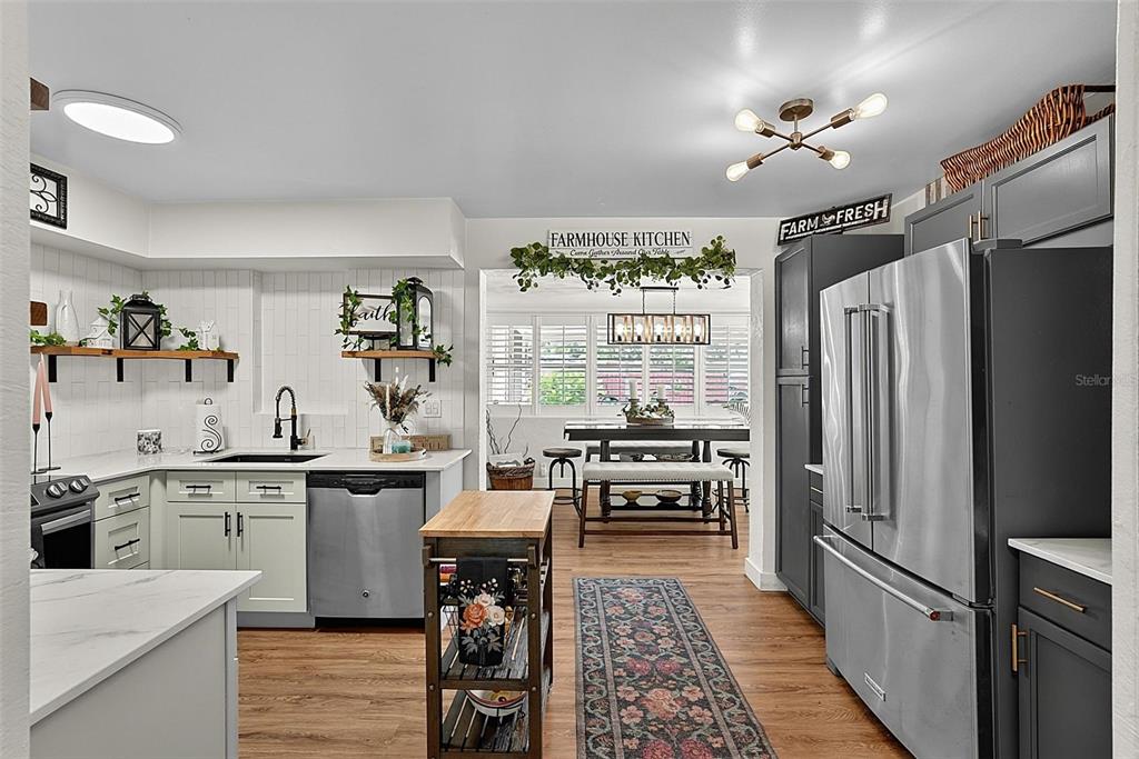 A kitchen with light-colored cabinets, a wooden island, and a dining area in the background — 715 STEELE AVENUE, SOUTH DAYTONA, FL