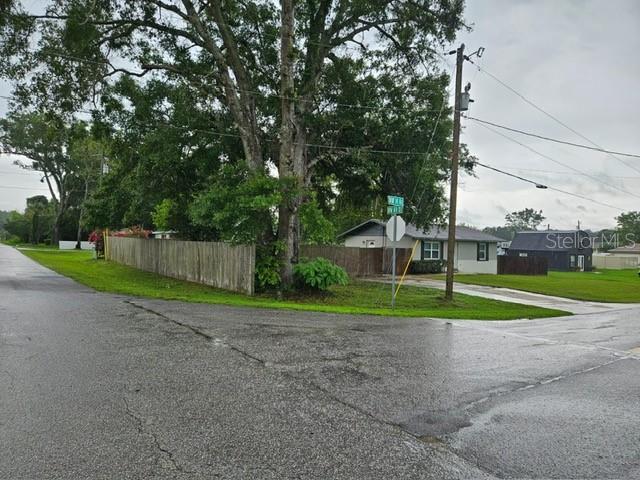 A street corner view shows a wooden fence, large trees, and a small residential house — 6881 NW 14TH AVENUE, OCALA, FL