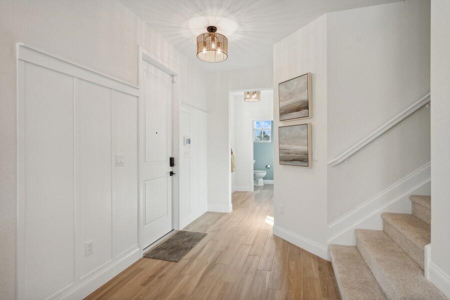A bright entryway features white board-and-batten walls, wood-look tile flooring, and a carpeted staircase — 194 SE Birch Terrace # 0316, Stuart FL 34997, STUART, FL