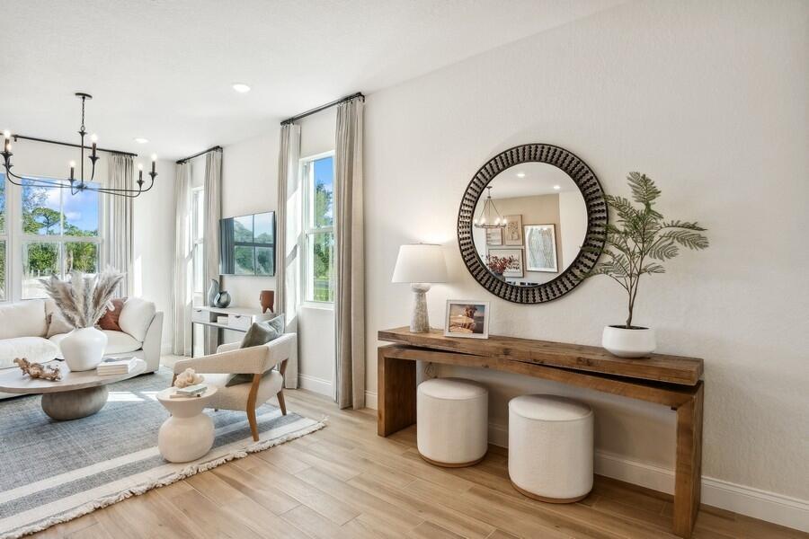 A bright living room features a wooden console table, round mirror, and neutral-toned furniture — 194 SE Birch Terrace # 0316, Stuart FL 34997, STUART, FL