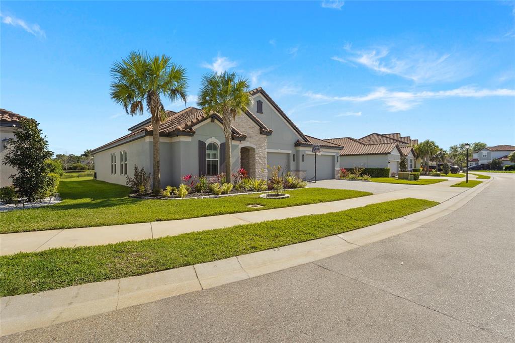 A single-story house with a tiled roof, stone accents, and palm trees in the front yard — 7208 GREAT EGRET BOULEVARD, SARASOTA, FL