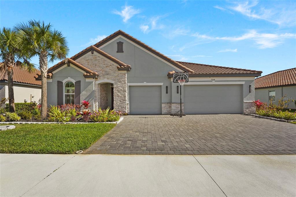A single-story house with a stone facade, a three-car garage, and a paved driveway — 7208 GREAT EGRET BOULEVARD, SARASOTA, FL