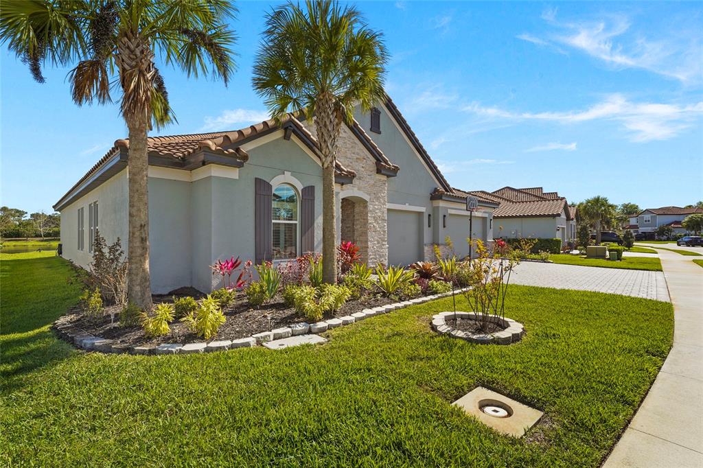 A single-story house with a stone facade, palm trees, and a paved driveway — 7208 GREAT EGRET BOULEVARD, SARASOTA, FL