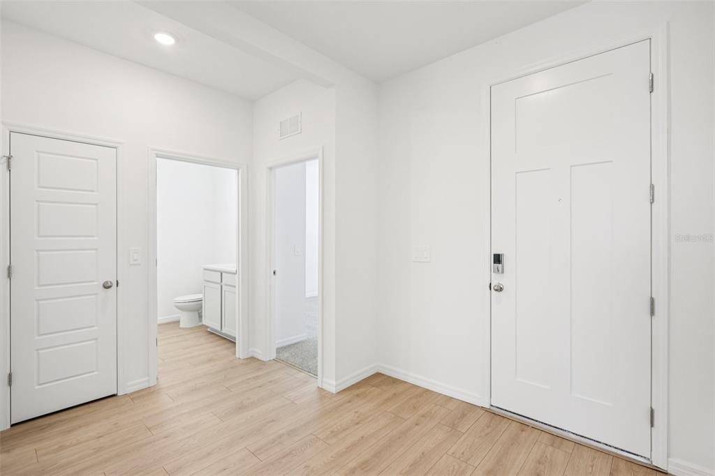 An interior view showing a white front door, two interior doors, and light wood flooring — 4664 BARBERRY AVENUE, LAKELAND, FL