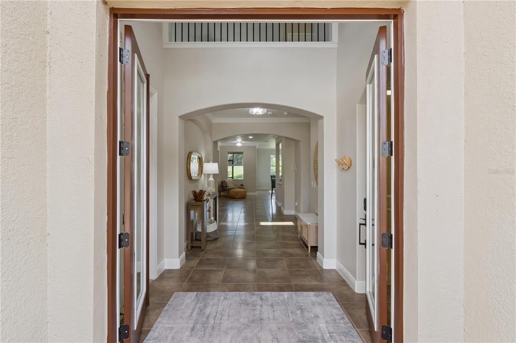 A view through an open double door into a tiled foyer with arched entryways — 2341 EAGLE TALON COURT, KISSIMMEE, FL