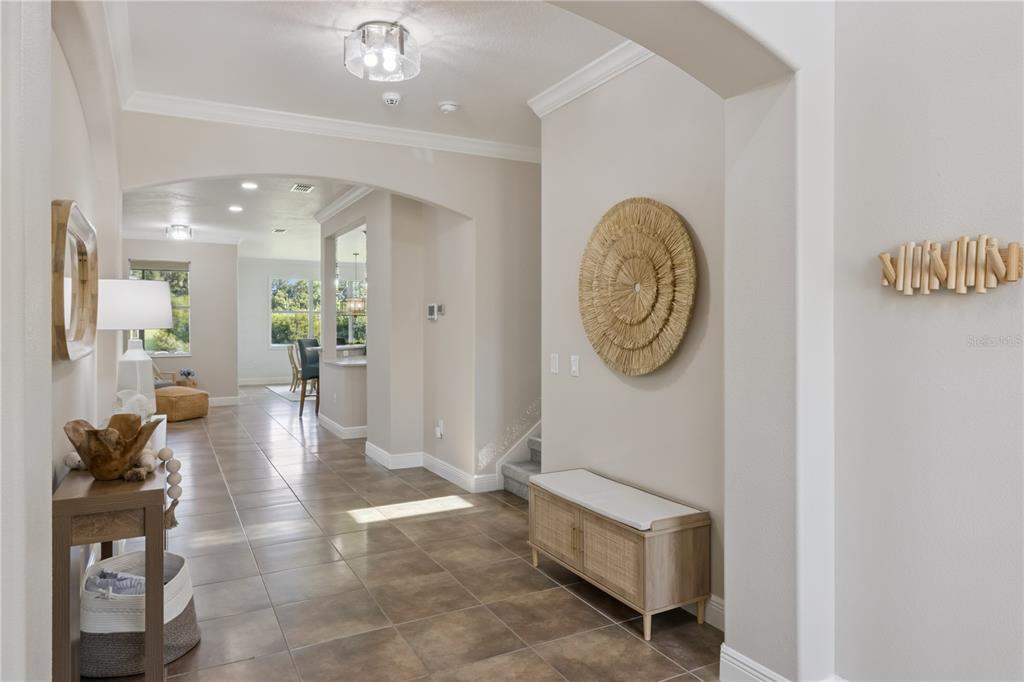 A tiled entryway features a wooden bench, a round wall decoration, and a console table — 2341 EAGLE TALON COURT, KISSIMMEE, FL