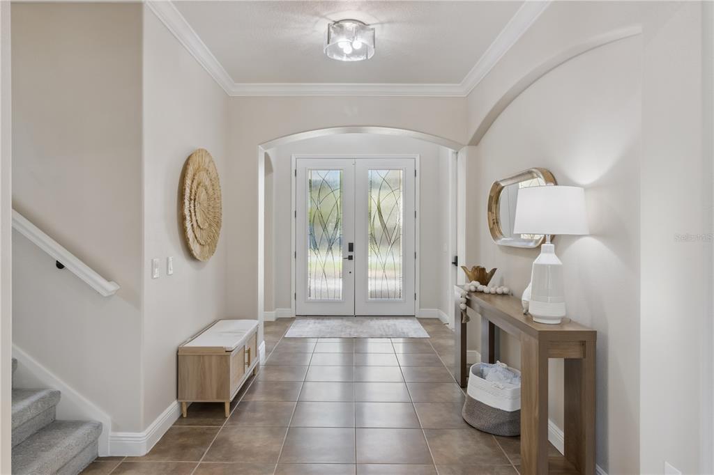 A bright entryway features tile flooring, a console table, a bench, and double glass doors — 2341 EAGLE TALON COURT, KISSIMMEE, FL