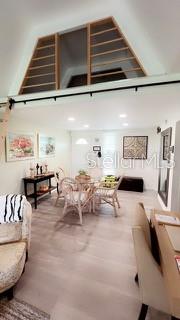 A dining area with a wicker table set sits beneath a loft with wooden railings — 4733 CLUB CIRCLE, LAKESHORE, FL