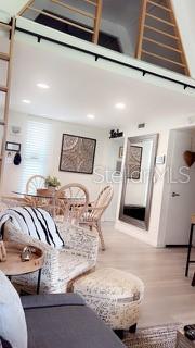 A living area with a loft, wicker furniture, a dining set, and a large wall mirror — 4733 CLUB CIRCLE, LAKESHORE, FL