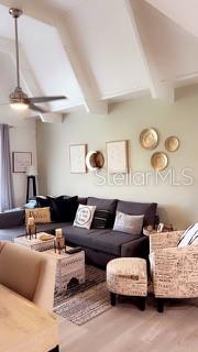 A living room features a gray sectional sofa, a patterned armchair, and a vaulted ceiling — 4733 CLUB CIRCLE, LAKESHORE, FL