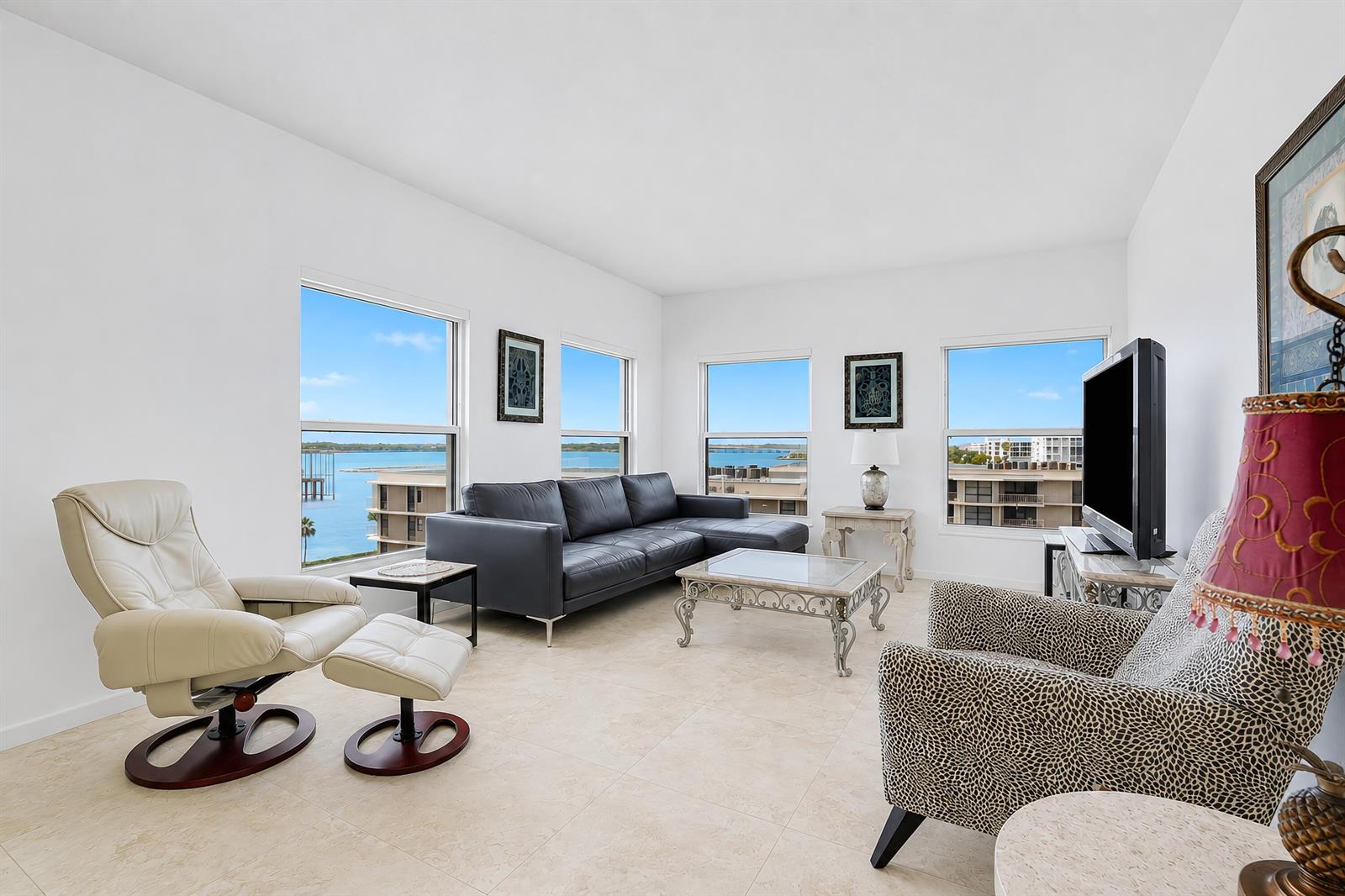 A living room with a leather sectional, recliner, and large windows overlooking the water — 3230 S Ocean Boulevard # 607, Palm Beach FL 33480, PALM BEACH, FL