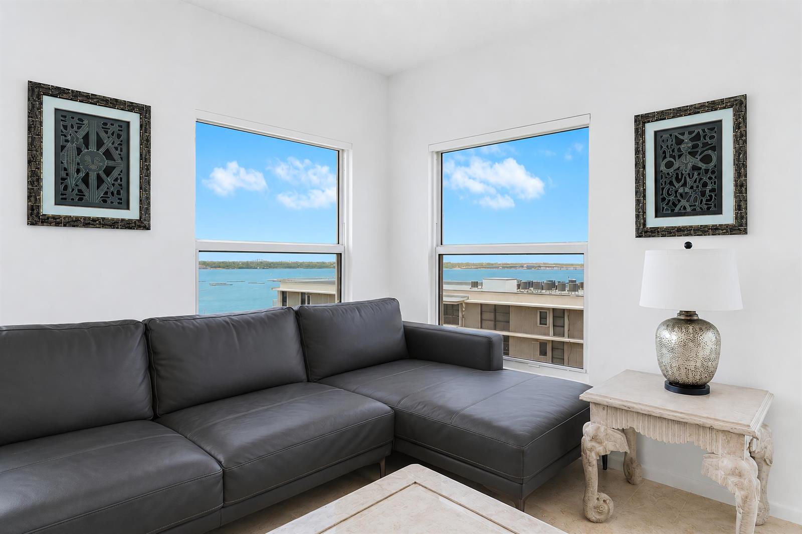 A living room features a dark leather sectional sofa, two framed artworks, and water views — 3230 S Ocean Boulevard # 607, Palm Beach FL 33480, PALM BEACH, FL