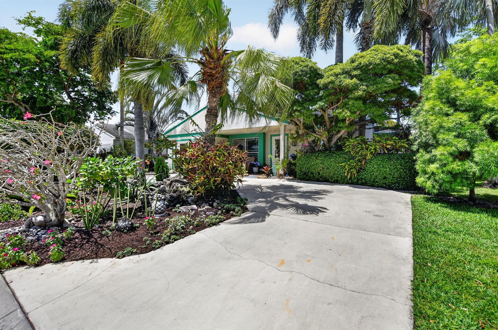A concrete driveway leads to the front entrance of a house surrounded by lush landscaping — 8353 Huntsman Place, Boca Raton FL 33433, BOCA RATON, FL