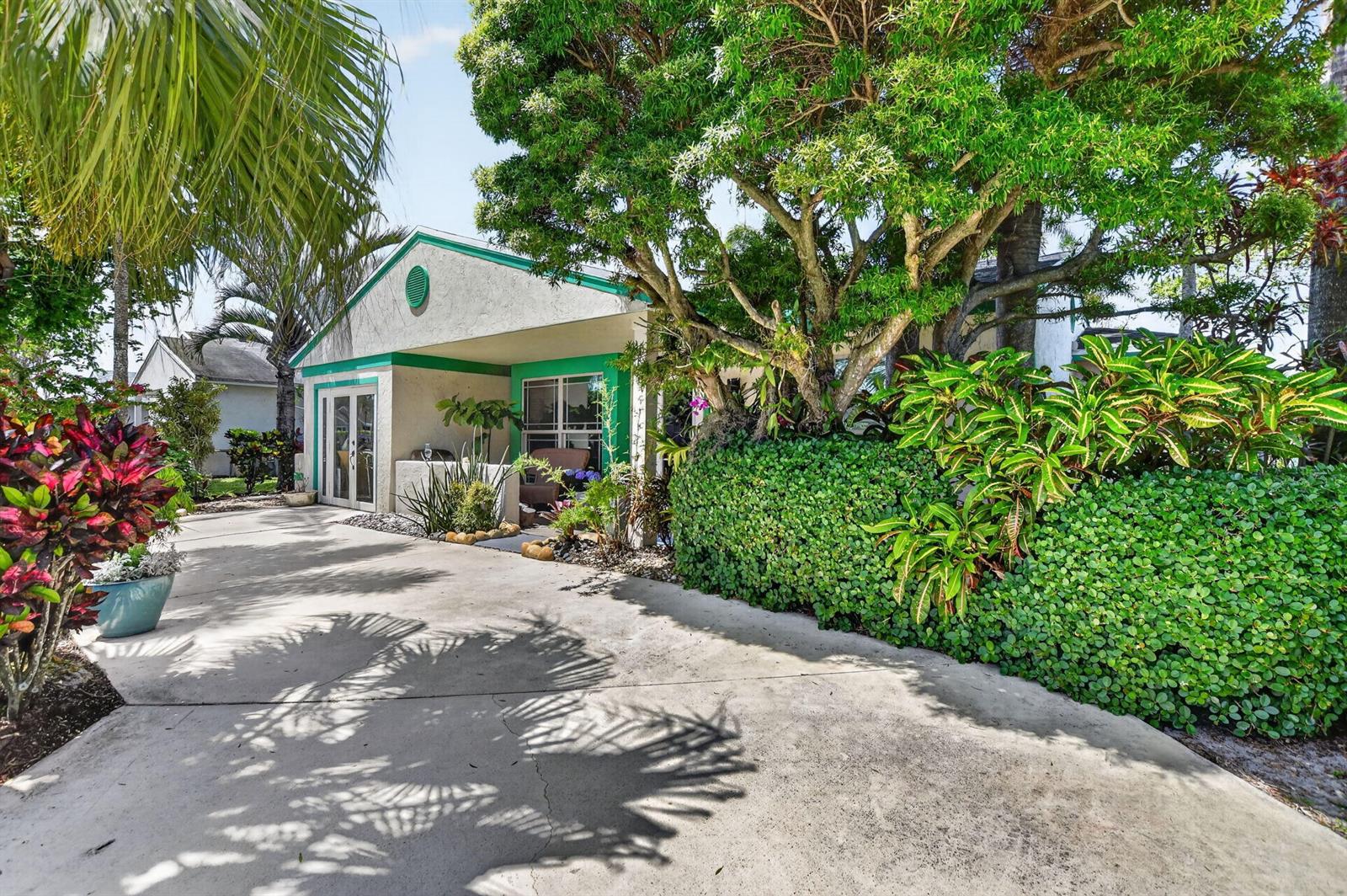 A single-story house with a concrete driveway, green trim, and lush landscaping — 8353 Huntsman Place, Boca Raton FL 33433, BOCA RATON, FL