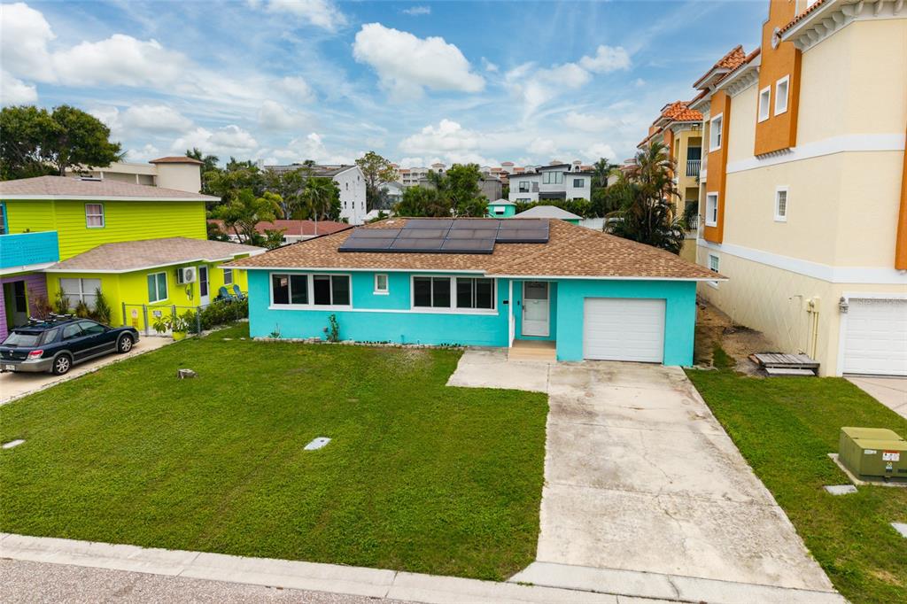 A turquoise single-story house with a shingled roof, solar panels, and a concrete driveway — 136 175TH TERRACE DRIVE E, REDINGTON SHORES, FL