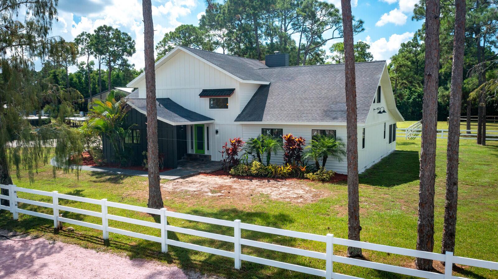 A two-story white farmhouse with a dark roof and a bright green front door — 13346/13026 Casey Road, FL 33470, FL