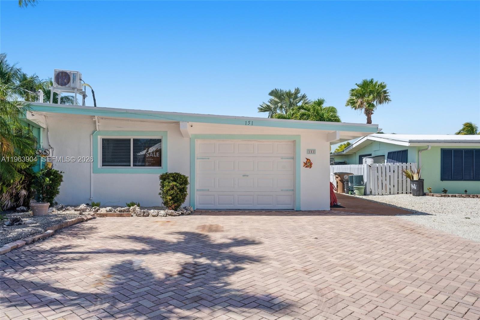 A single-story house with a white exterior, turquoise trim, and a paved driveway — 151 10th St, Marathon FL 33051, MARATHON, FL