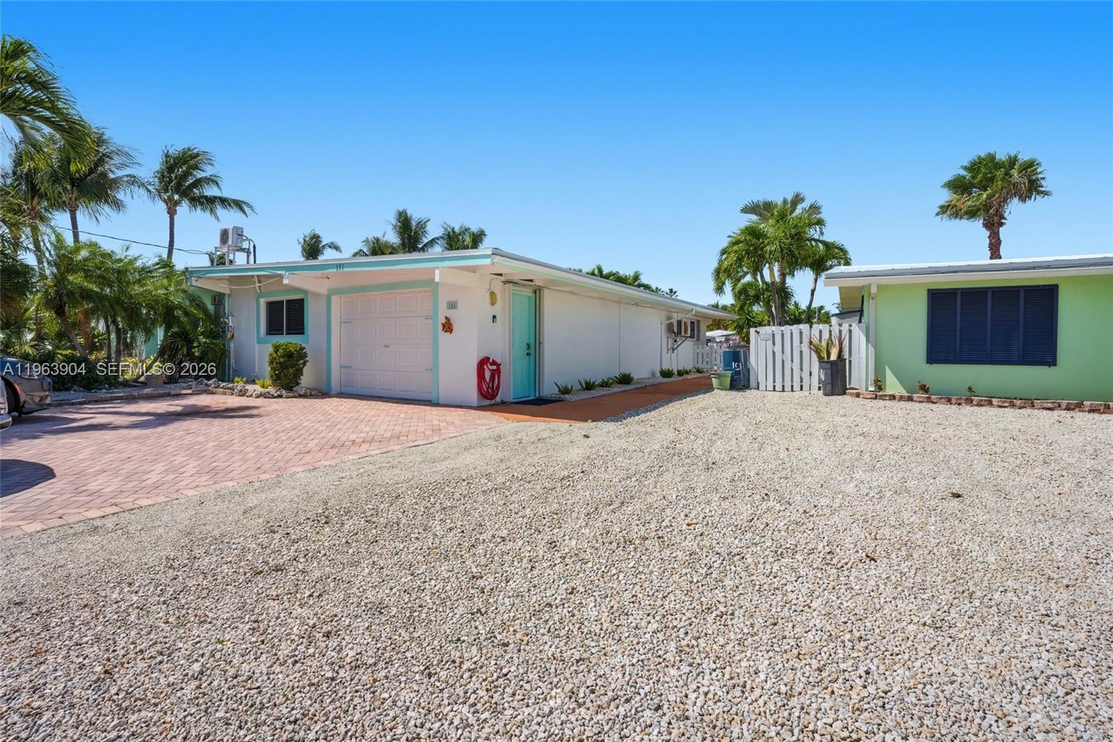 A single-story house with a white garage, turquoise trim, and a gravel driveway — 151 10th St, Marathon FL 33051, MARATHON, FL