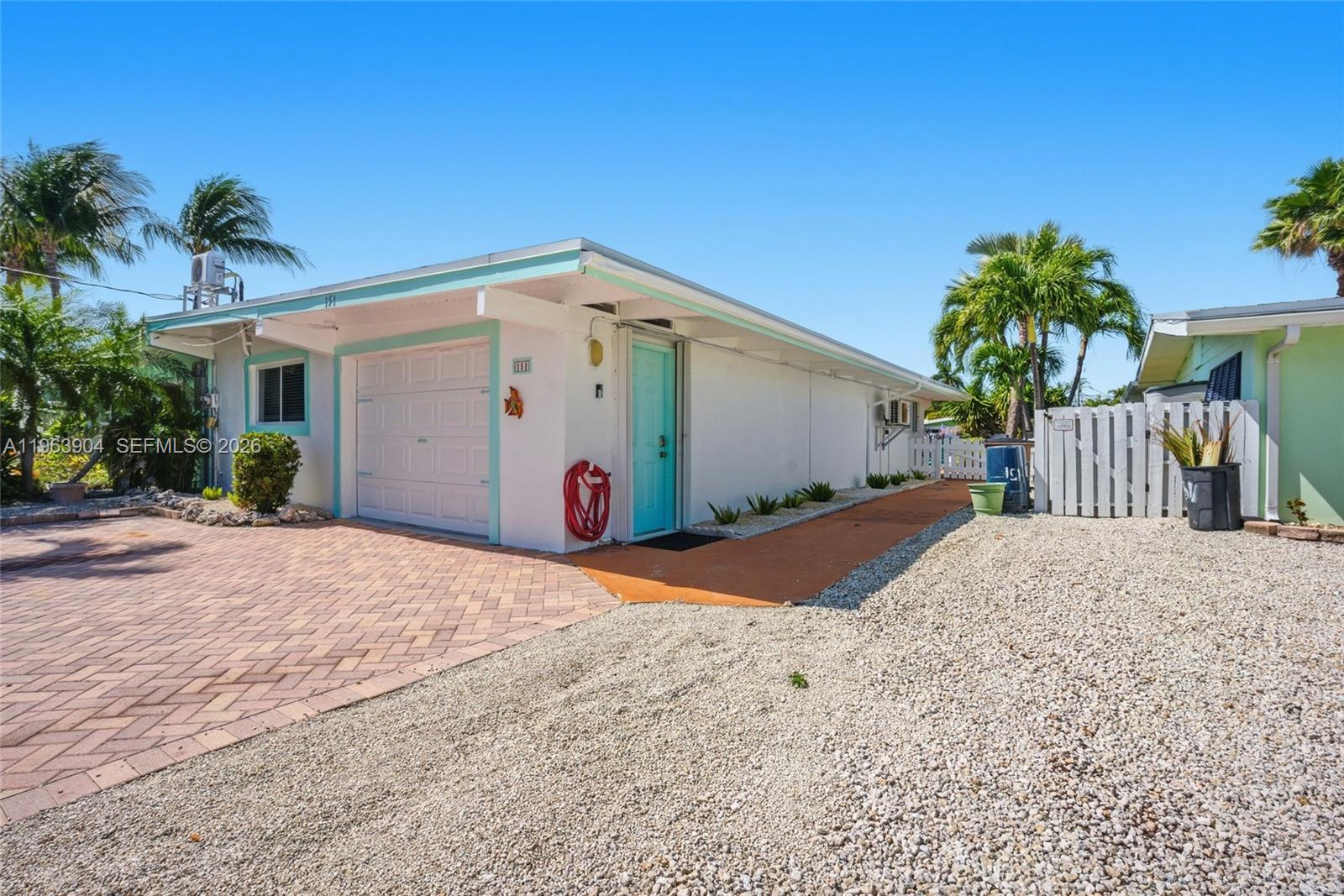 A single-story house with a white exterior, turquoise trim, a garage, and a gravel driveway — 151 10th St, Marathon FL 33051, MARATHON, FL