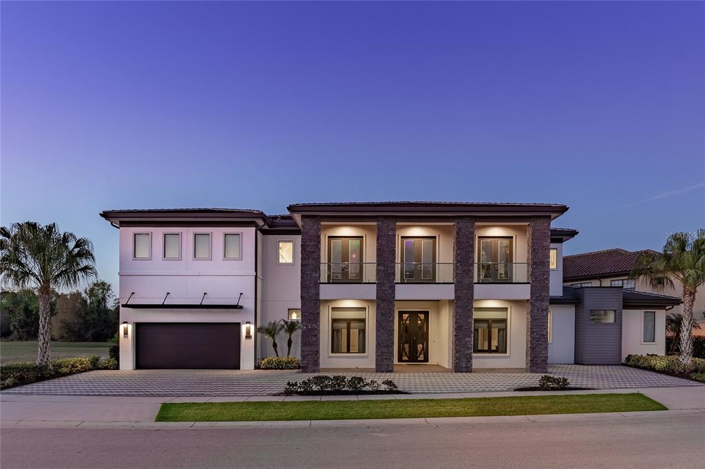A two-story modern house with a stone facade, a garage, and a paved driveway — 1200 GRAND TRAVERSE PARKWAY, REUNION, FL