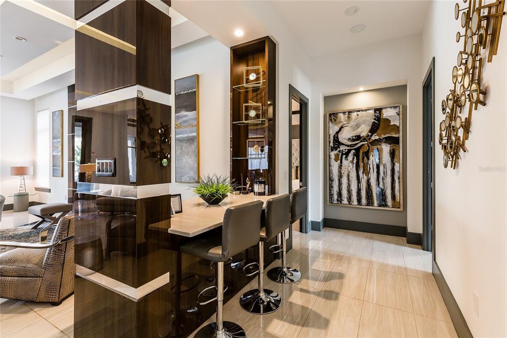 A modern home bar area features a stone countertop, three stools, and dark wood cabinetry — 1200 GRAND TRAVERSE PARKWAY, REUNION, FL