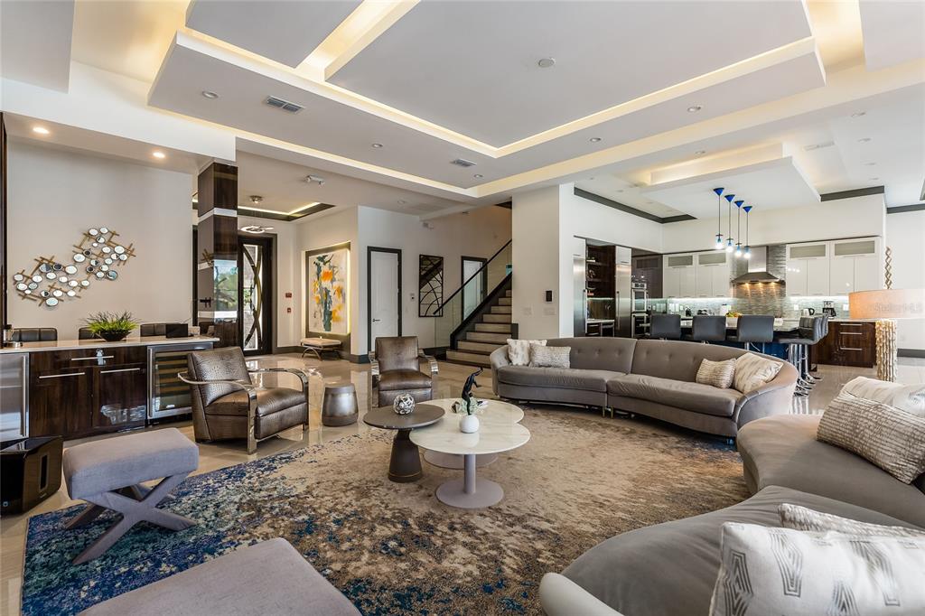 A spacious open-concept living room features a curved sofa, modern lighting, and a kitchen area — 1200 GRAND TRAVERSE PARKWAY, REUNION, FL