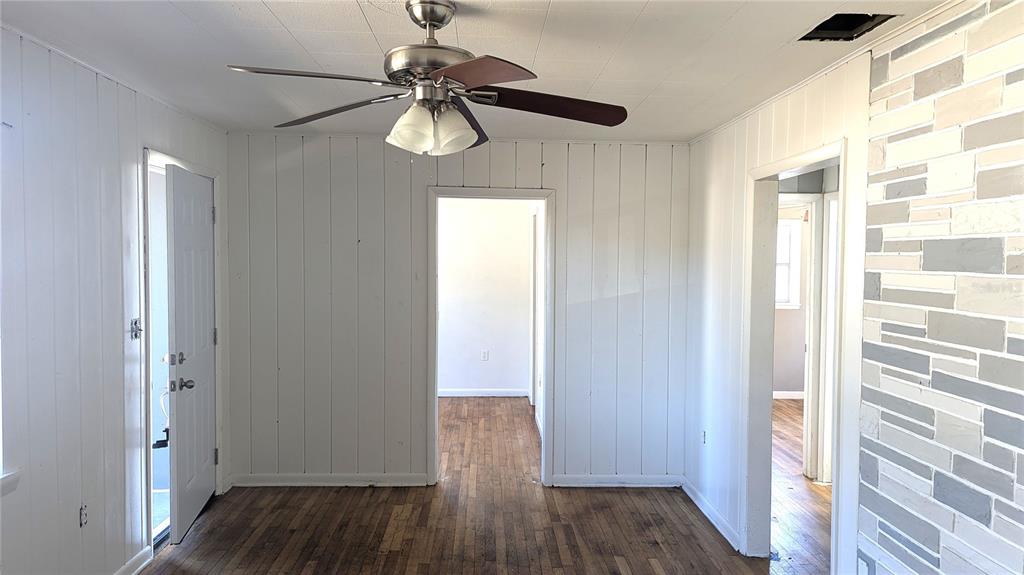 A room with white vertical wood paneling, a ceiling fan, and a stone-look accent wall — 3425 IRENE STREET, MELBOURNE, FL