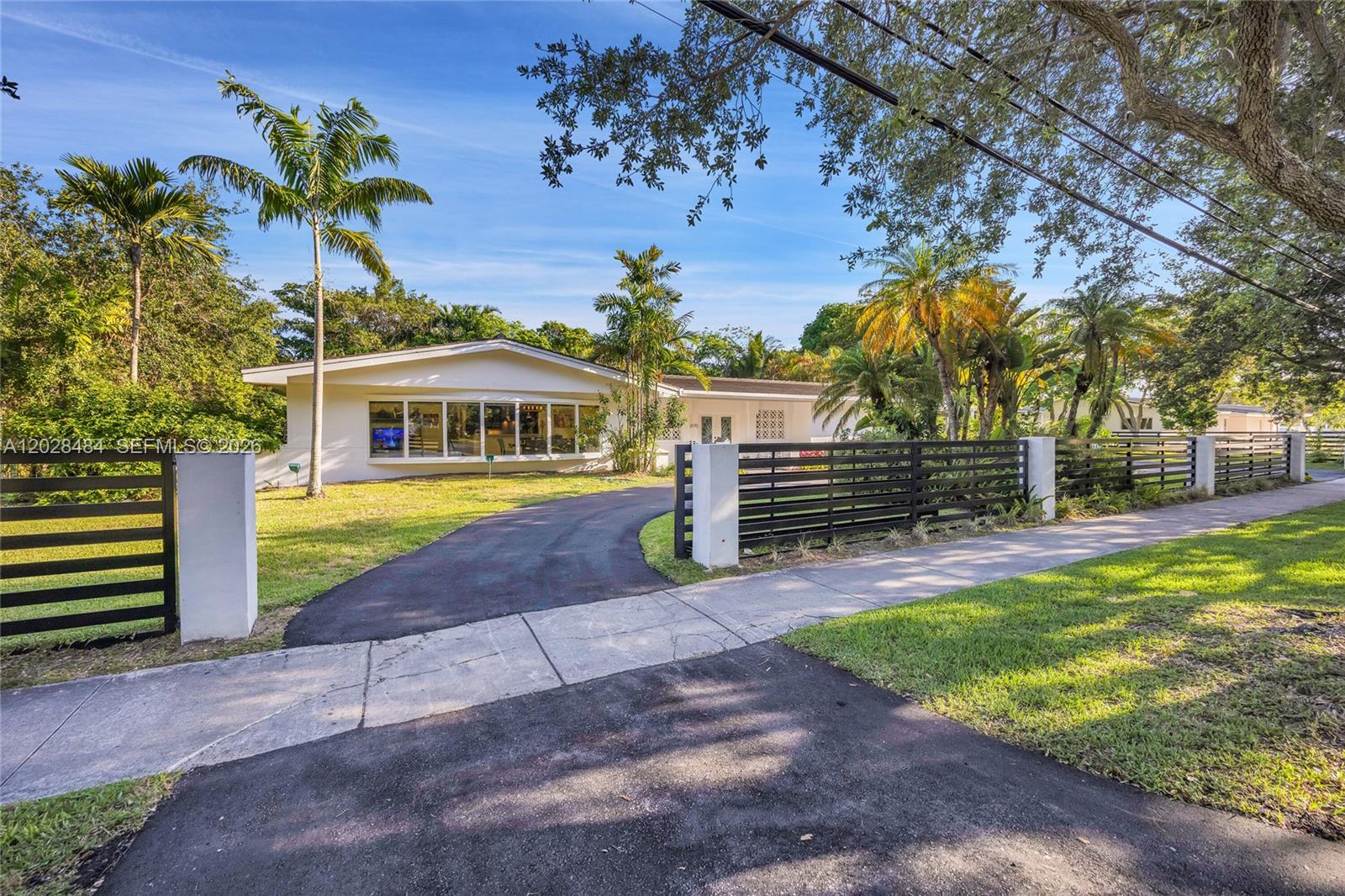 A single-story house with a curved driveway and a modern horizontal slat fence — 6970 SW 124th St, Pinecrest FL 33156, PINECREST, FL
