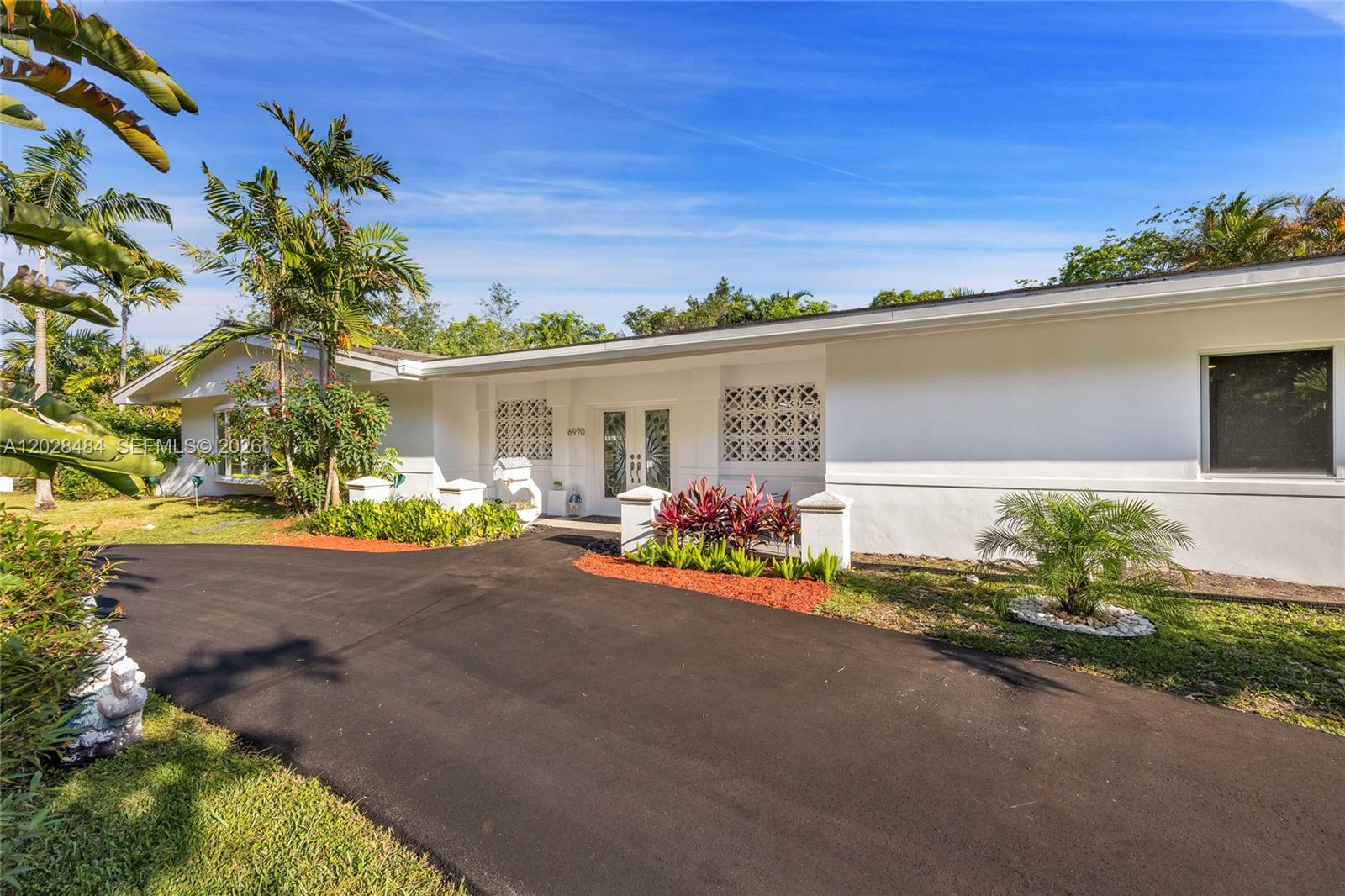 A white single-story house features a black asphalt driveway and decorative concrete block screens — 6970 SW 124th St, Pinecrest FL 33156, PINECREST, FL