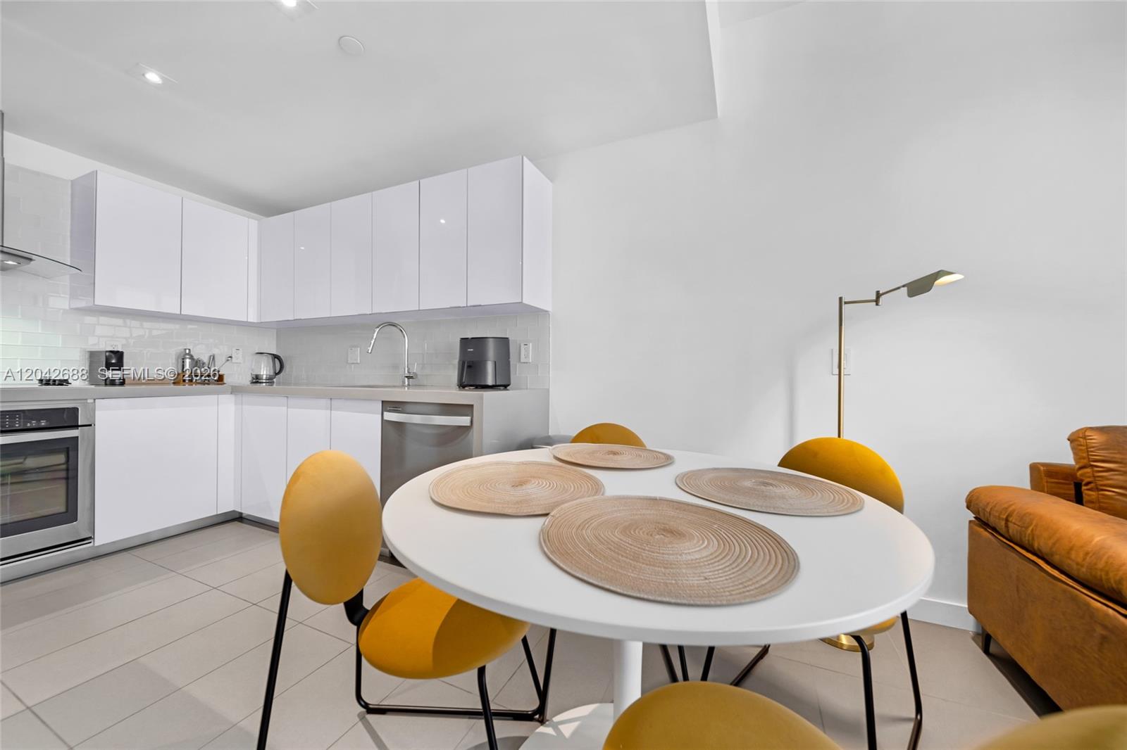 A modern kitchen features white cabinetry, stainless steel appliances, and a round dining table — 1600 NE 1st Ave # 2318, Miami FL 33132, MIAMI, FL
