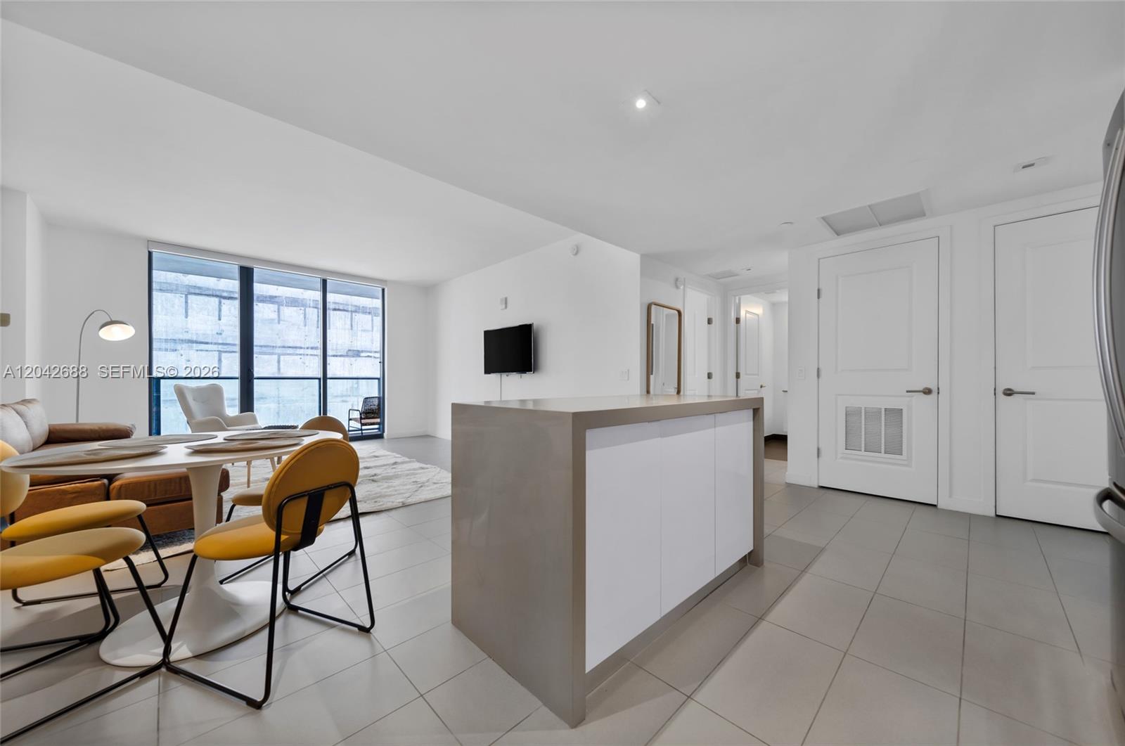 An open-concept living and dining area features a kitchen island, tile floors, and floor-to-ceiling windows — 1600 NE 1st Ave # 2318, Miami FL 33132, MIAMI, FL