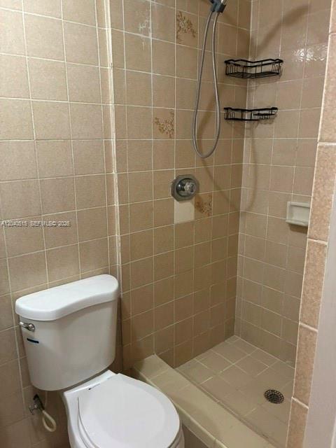 A bathroom features a white toilet next to a tiled walk-in shower with metal shelves — 6741 SW 5th Ter, Miami FL 33144, MIAMI, FL